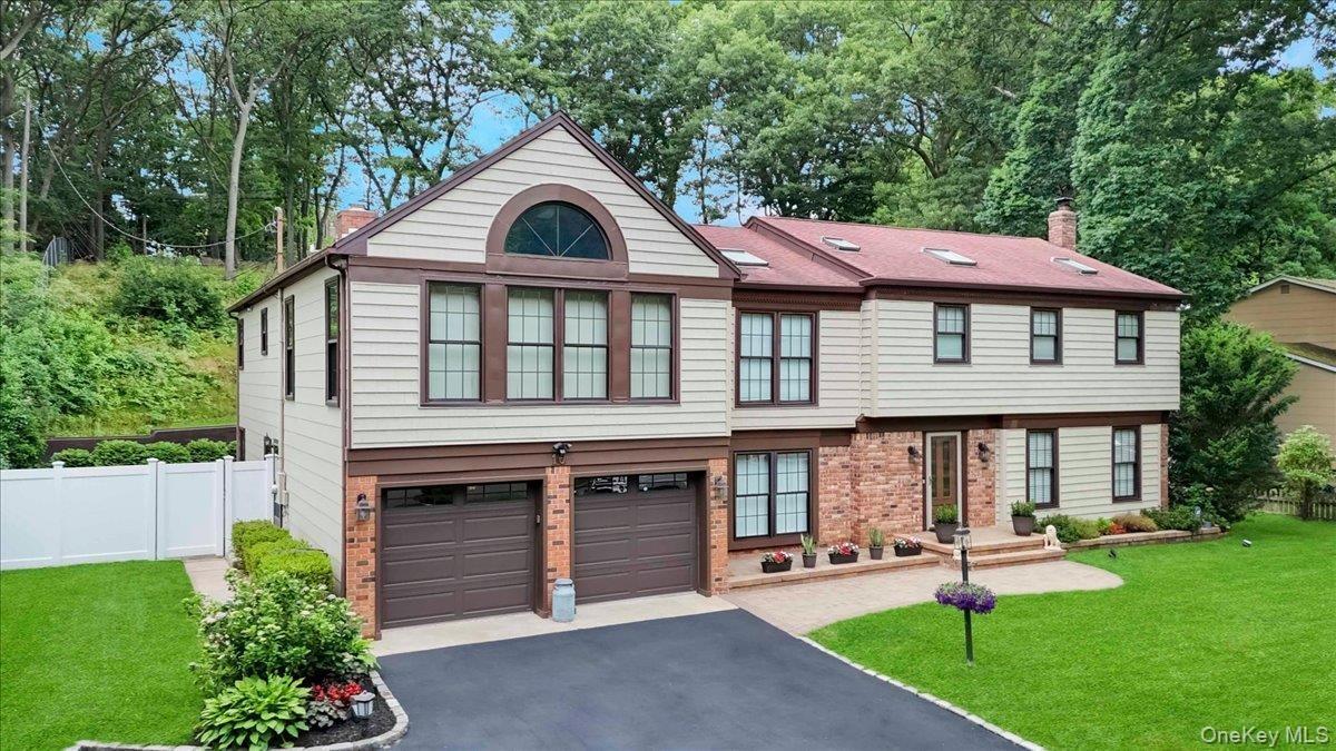 Two-story residence featuring light-toned siding with brown trim accents, a red shingle roof with skylights, and a brick facade detail