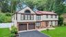 Two-story residence featuring light-toned siding with brown trim accents, a red shingle roof with skylights, and a brick facade detail