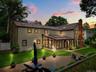 Expansive rear exterior featuring a paved patio and a glass-enclosed sunroom with skylights