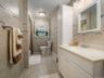 Full bathroom with a white vanity featuring a light-toned countertop, a framed mirror, and a white storage cabinet