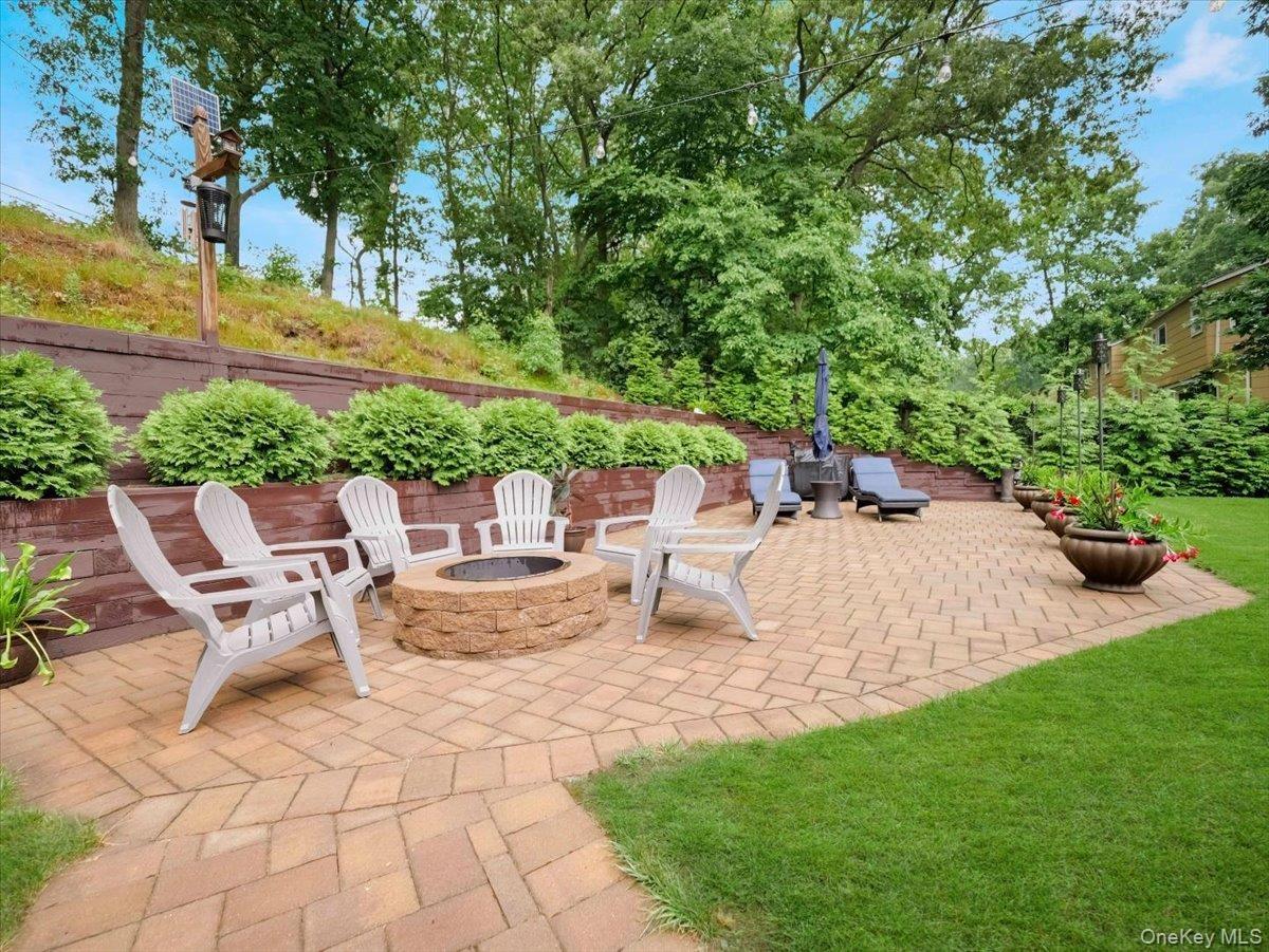 Expansive paver patio featuring a built-in stone fire pit