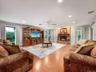 Spacious living area featuring wood-finish flooring, a prominent brick fireplace, and recessed lighting