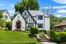 Tudor-style residence featuring a white stucco exterior with dark timber accents and a stone archway entrance