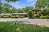 Ranch-style residence featuring a brick facade with cedar shake siding, a multi-car driveway, and integrated outdoor lighting