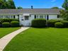 Single-story residence featuring white siding, a dark shingle roof, and black window shutters