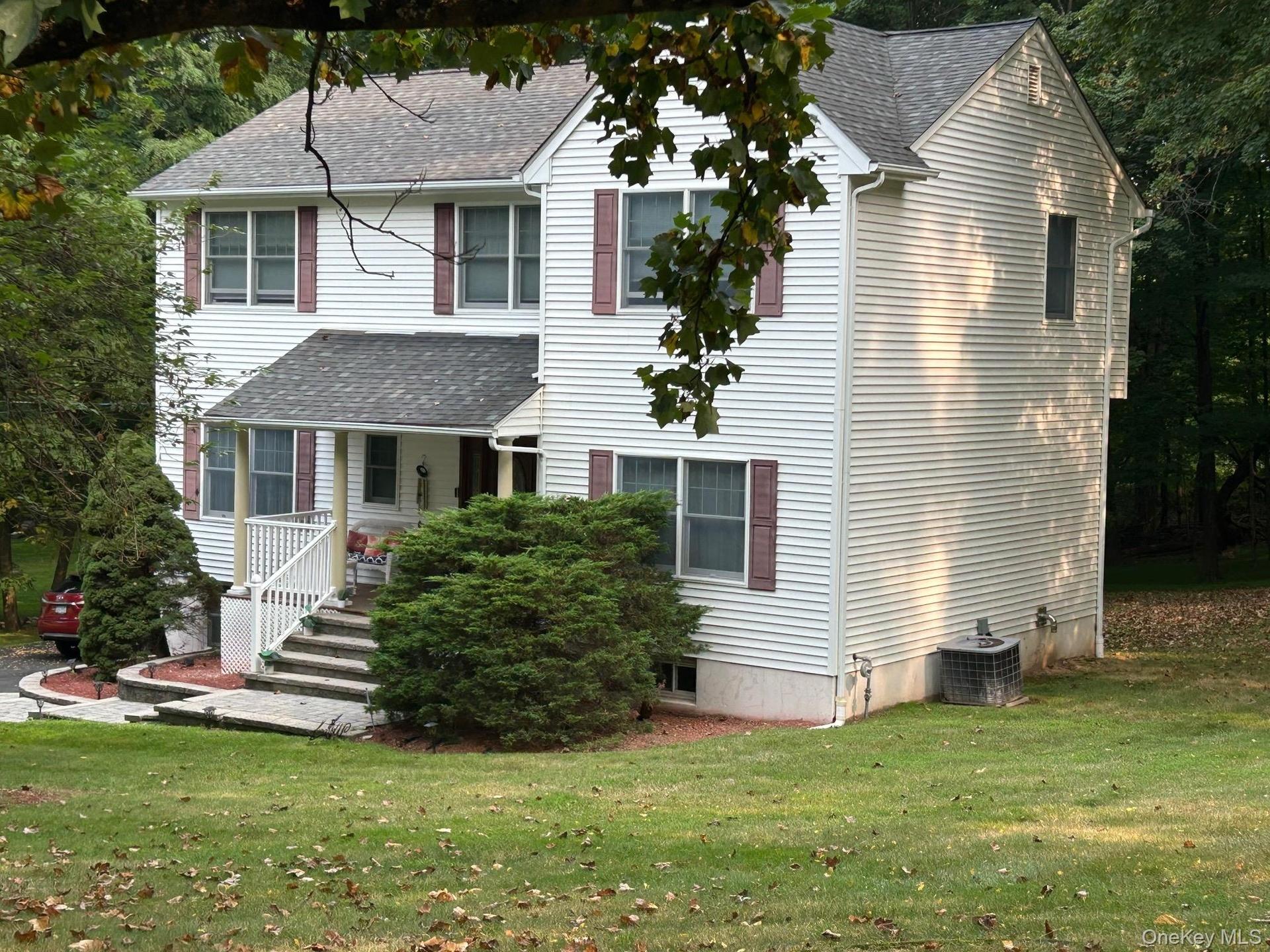 View of front of home featuring a shingled roof, a porch, and a front yard
