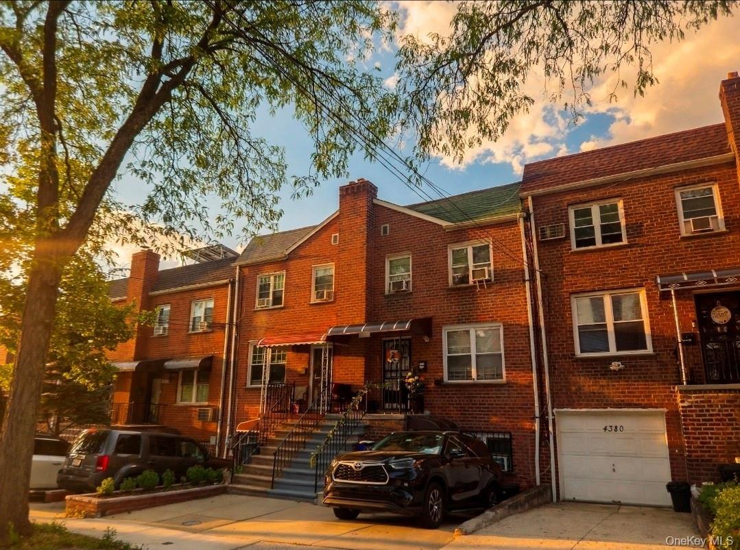 Brick facade residence featuring multiple windows, a front porch with an awning, and a private driveway