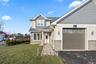 Craftsman house with stone siding, a front yard, and roof with shingles