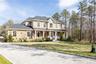 View of front of home featuring a standing seam roof, covered porch, a shingled roof, a metal roof, and a front lawn