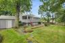 Spacious backyard featuring a manicured lawn, established trees