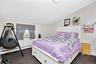 Bedroom with vaulted ceiling, dark carpet, cooling unit, and a baseboard radiator