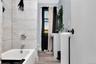 Bathroom with wood finished floors, shower / tub combination, radiator heating unit, and vanity