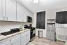 Kitchen featuring stainless steel appliances, radiator heating unit, cooling unit, light wood-style floors, and backsplash