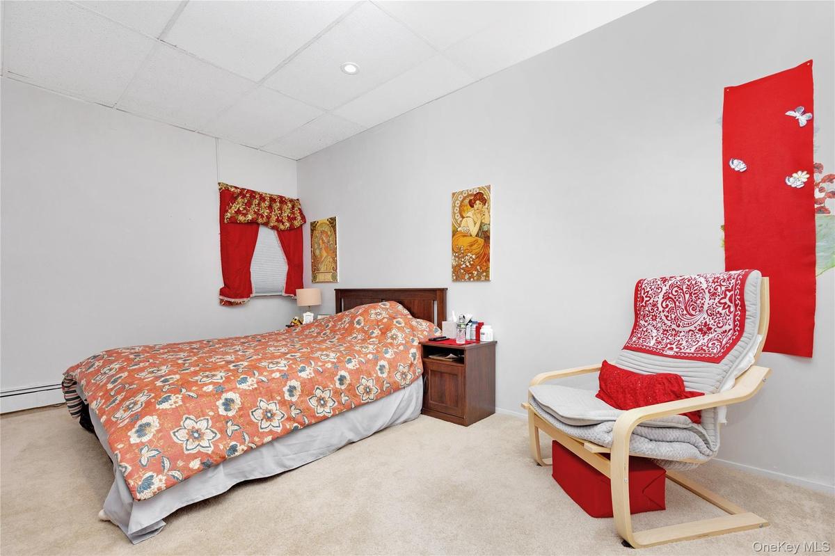 Carpeted bedroom with a drop ceiling and a baseboard heating unit