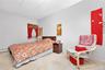 Carpeted bedroom with a drop ceiling and a baseboard heating unit