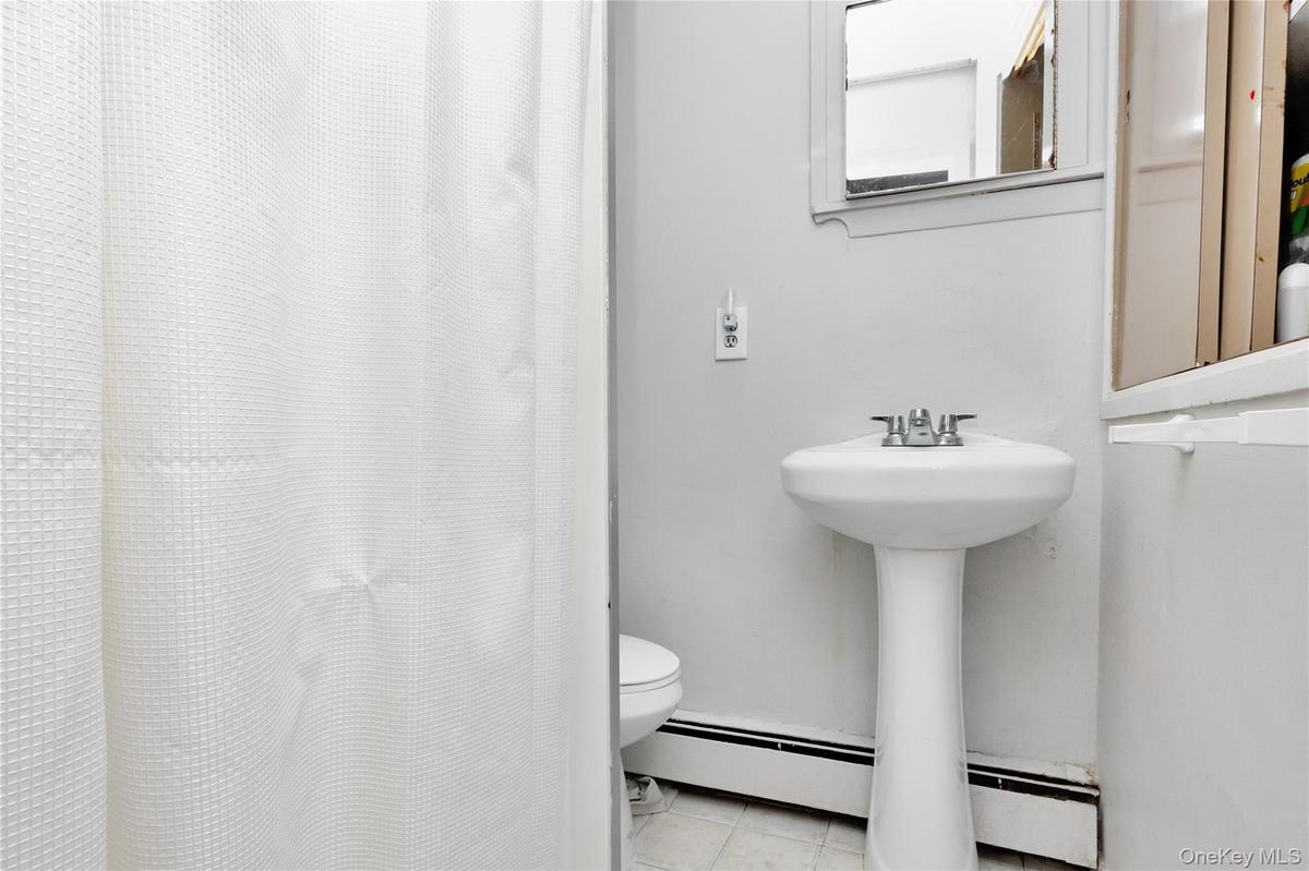 Bathroom with tile patterned flooring, a baseboard heating unit, and curtained shower