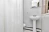 Bathroom with tile patterned flooring, a baseboard heating unit, and curtained shower