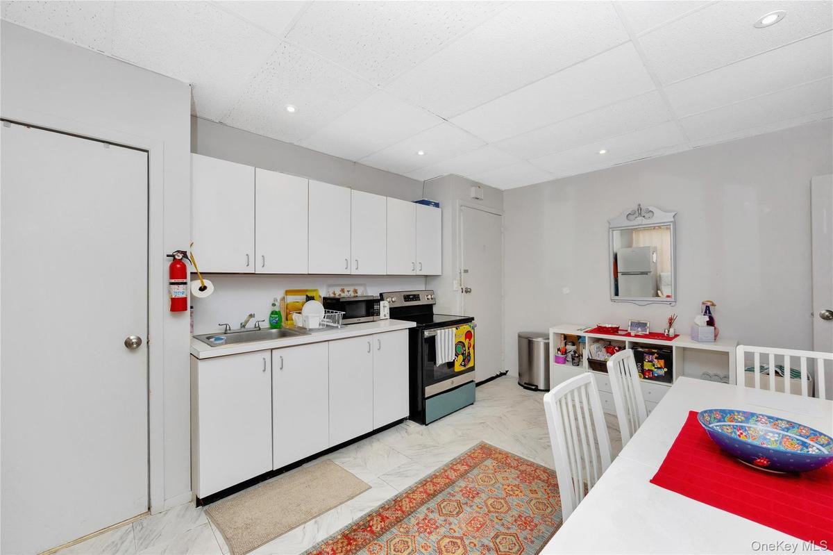 Kitchen with appliances with stainless steel finishes, light countertops, a paneled ceiling, white cabinets, and recessed lighting