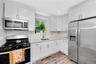 Kitchen featuring appliances with stainless steel finishes, light countertops, white cabinetry, light wood-style flooring, and decorative backsplash