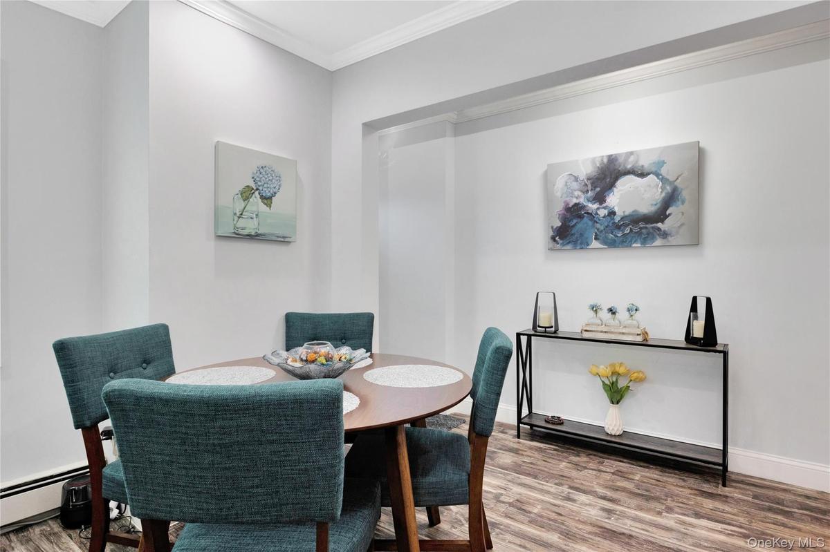 Dining area featuring wood finished floors, ornamental molding, and a baseboard heating unit