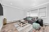 Living area featuring a baseboard heating unit, wood finished floors, crown molding, and recessed lighting