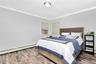 Bedroom featuring ornamental molding, a baseboard heating unit, wood finished floors, and cooling unit