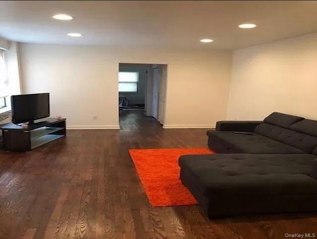 Living area with recessed lighting, plenty of natural light, dark wood-type flooring, and baseboards