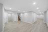 Spacious interior featuring light wood-finish flooring, recessed lighting, neutral wall tones, white trim, and a visible staircase with wood treads