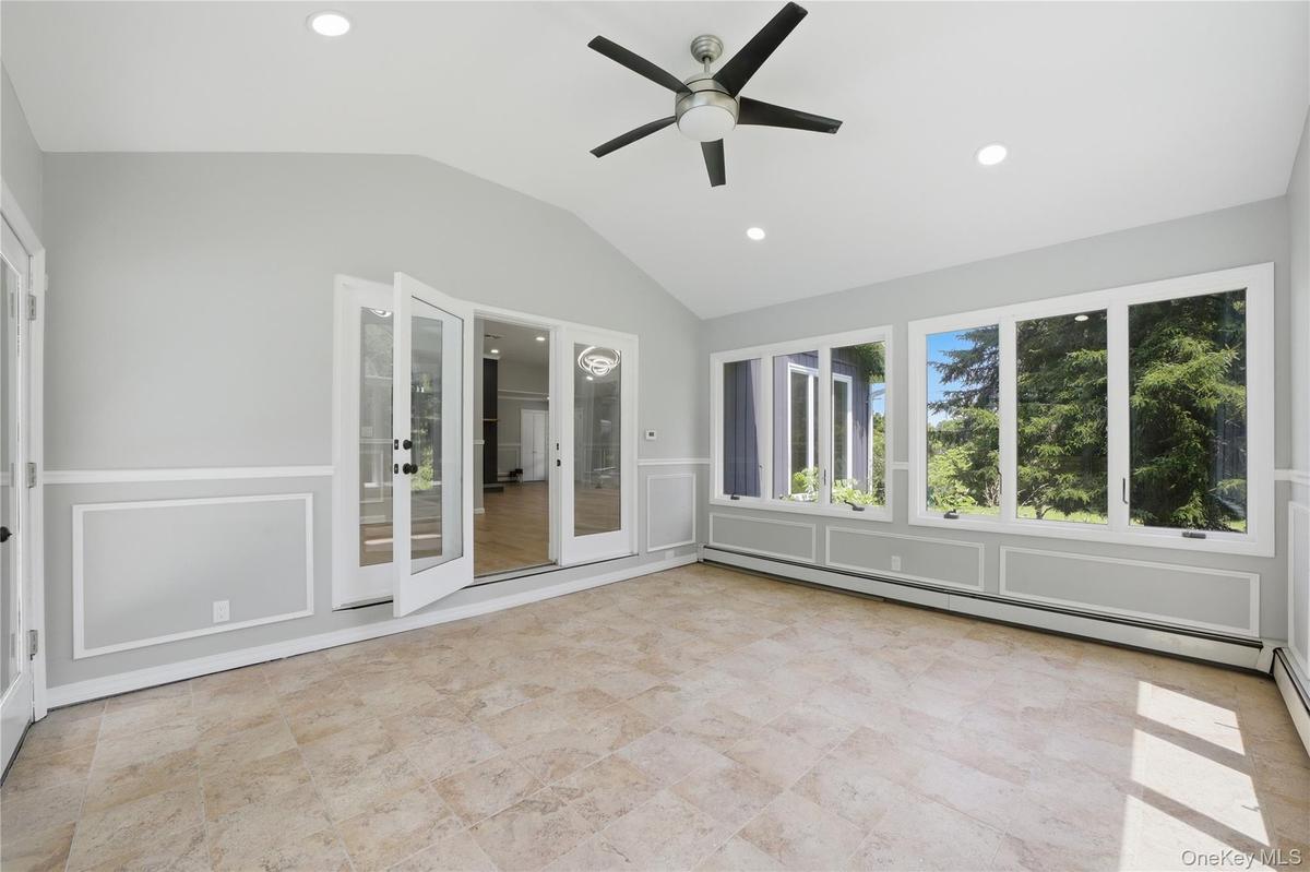 Light-filled room featuring large windows, a vaulted ceiling, recessed lighting, a ceiling fan, and tile flooring