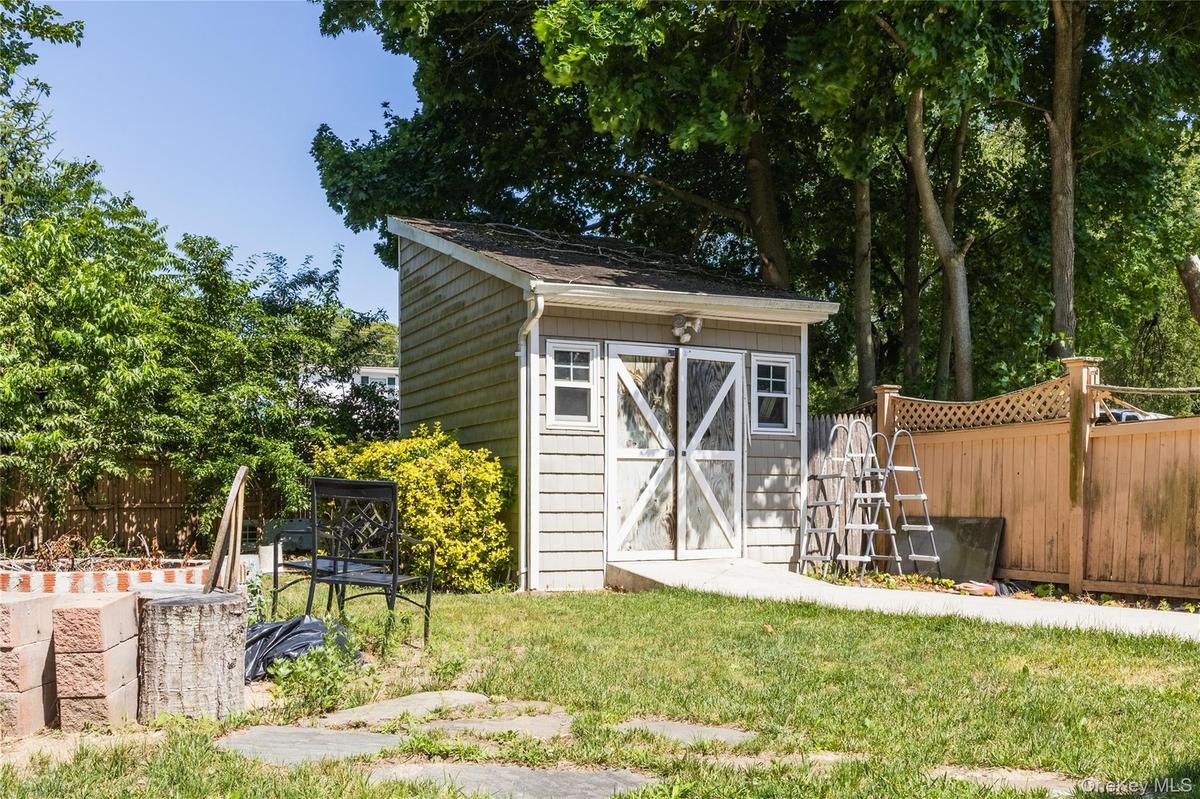 Storage shed with shingle siding, an asphalt shingle roof, and white-framed windows