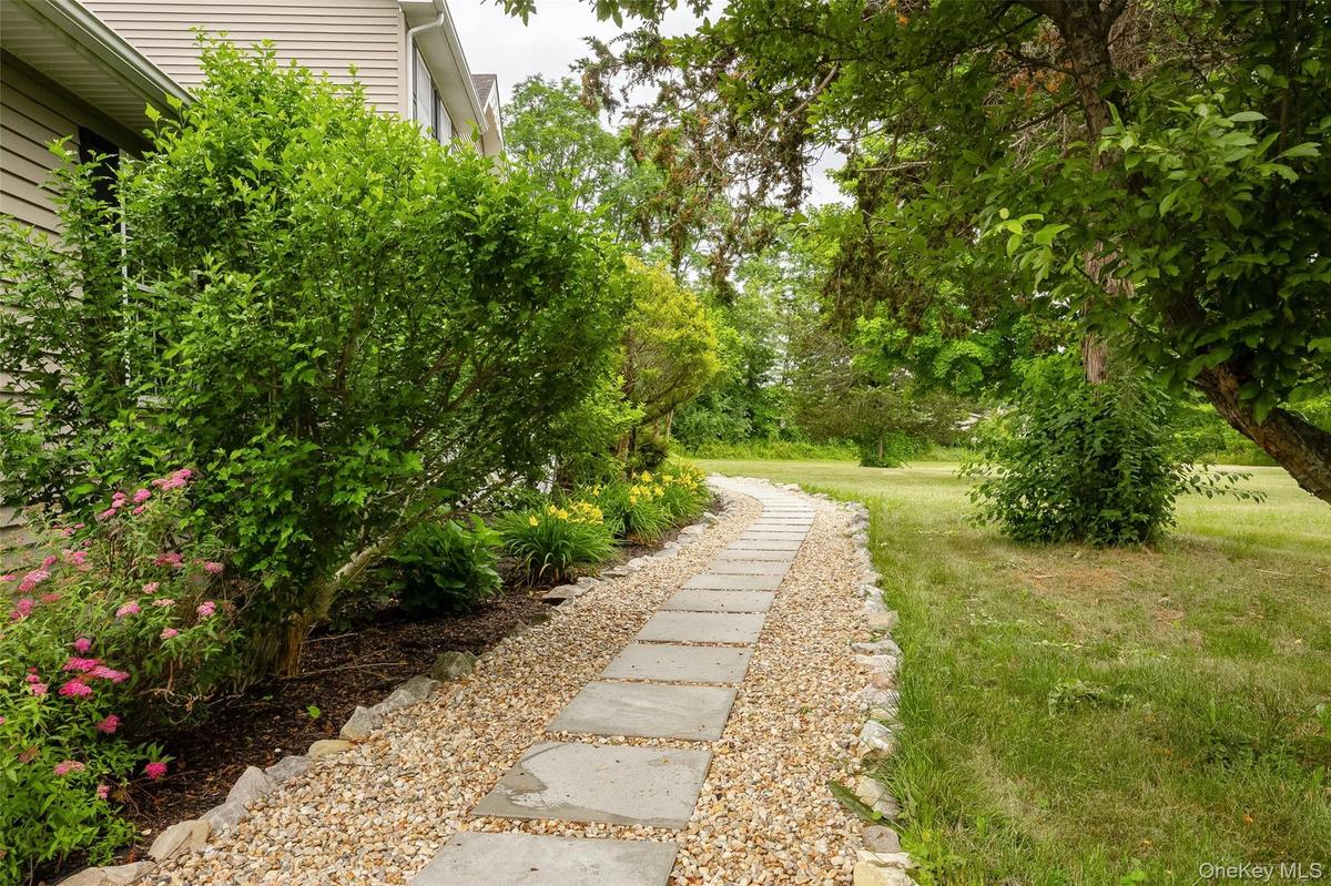 Curved stepping stone pathway bordered by gravel, leading through a spacious lawn