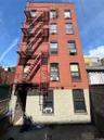 Red brick exterior facade featuring multiple windows and a multi-level fire escape system