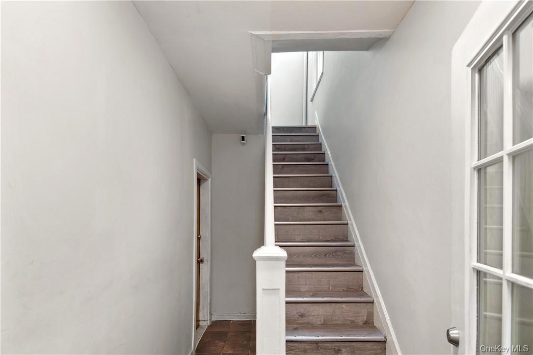 Staircase featuring wood-finish treads and white risers, framed by a white newel post and handrail