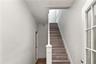 Staircase featuring wood-finish treads and white risers, framed by a white newel post and handrail