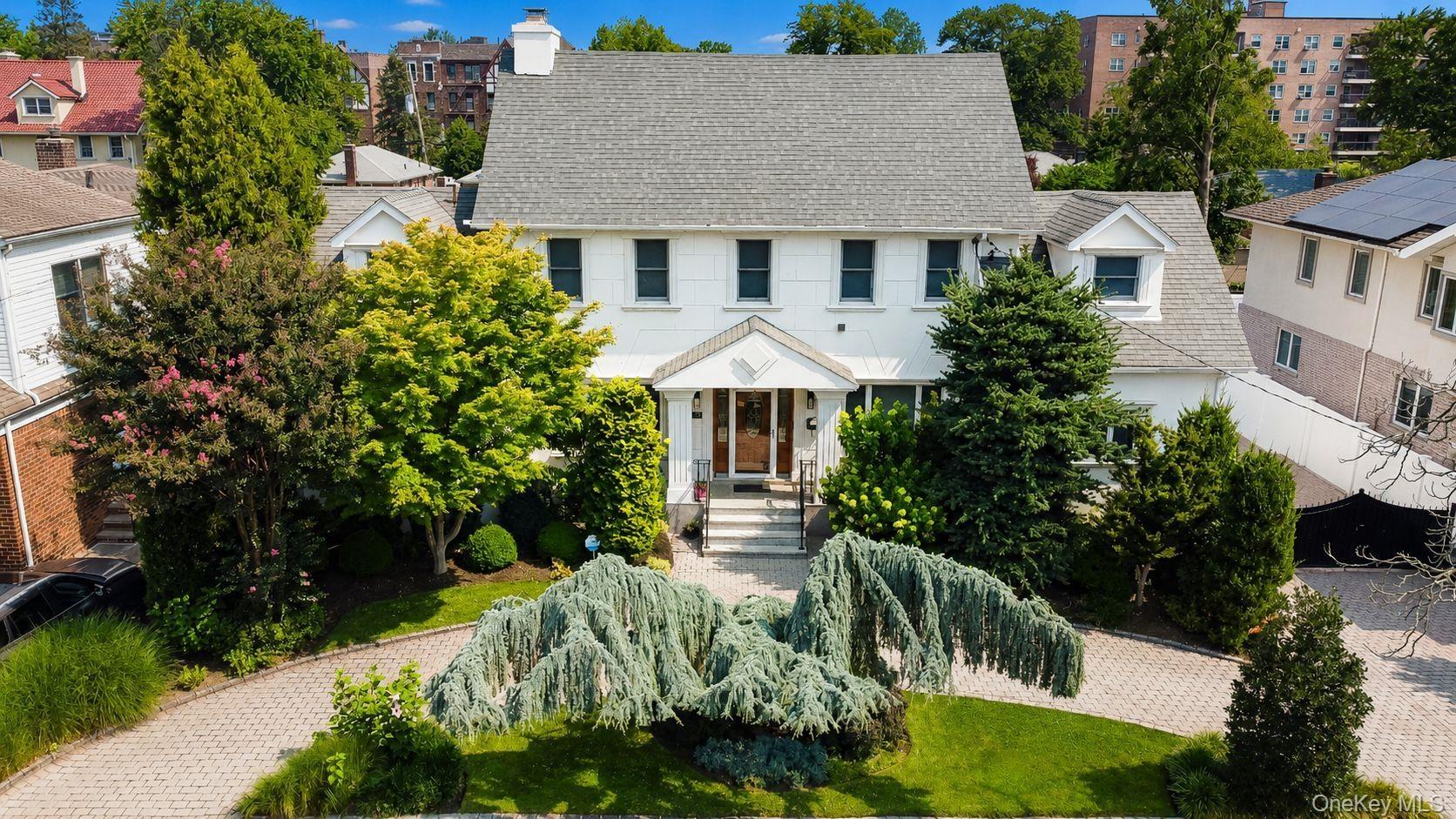 White Colonial-style residence featuring a gray shingle roof and multiple dormer windows