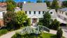 White Colonial-style residence featuring a gray shingle roof and multiple dormer windows