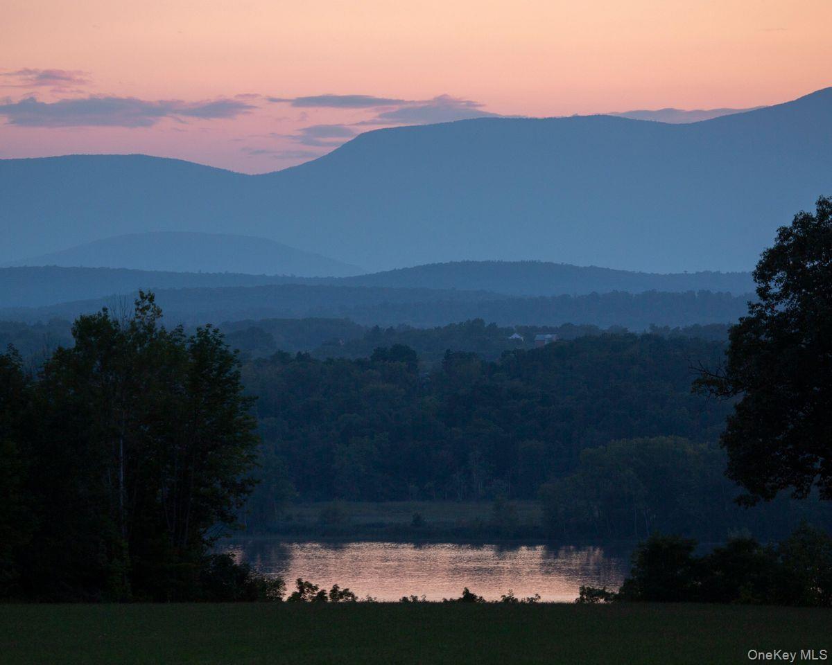 Property view of mountains featuring a water view and a forest view