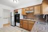 Kitchen featuring granite countertops and backsplash, wood cabinetry, stainless steel gas range, and an undermount sink with a gooseneck faucet