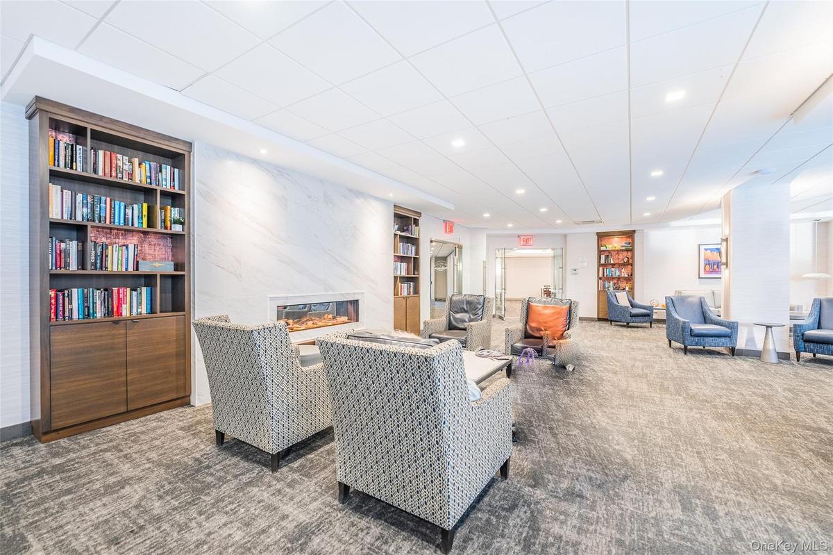 Carpeted living room featuring built in shelves, a high end fireplace, and recessed lighting