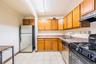 Kitchen featuring stainless steel appliances, light stone counters, brown cabinets, a textured ceiling, and light tile patterned floors