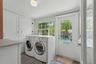 A bright and functional laundry room offers generous built-in storage, full-size washer and dryer space, and direct access to the pool and backyard.