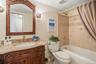 The hallway bathroom features a large wood vanity, mirror and full size soaking tub with a tiled enclosure.