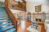 Open-concept living area featuring wood-finish, vinyl flooring, a two-story vaulted ceiling and a prominent staircase with wood railings leading to th