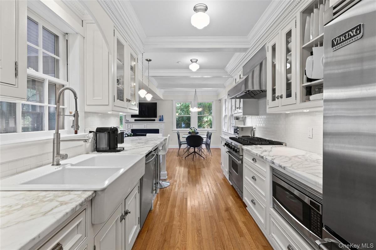 Kitchen featuring hardwood flooring, custom cabinetry, Wolf stainless steel appliances,  marble counter tops, white subway tile backsplash, and a brea