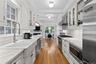 Kitchen featuring hardwood flooring, custom cabinetry, Wolf stainless steel appliances,  marble counter tops, white subway tile backsplash, and a brea