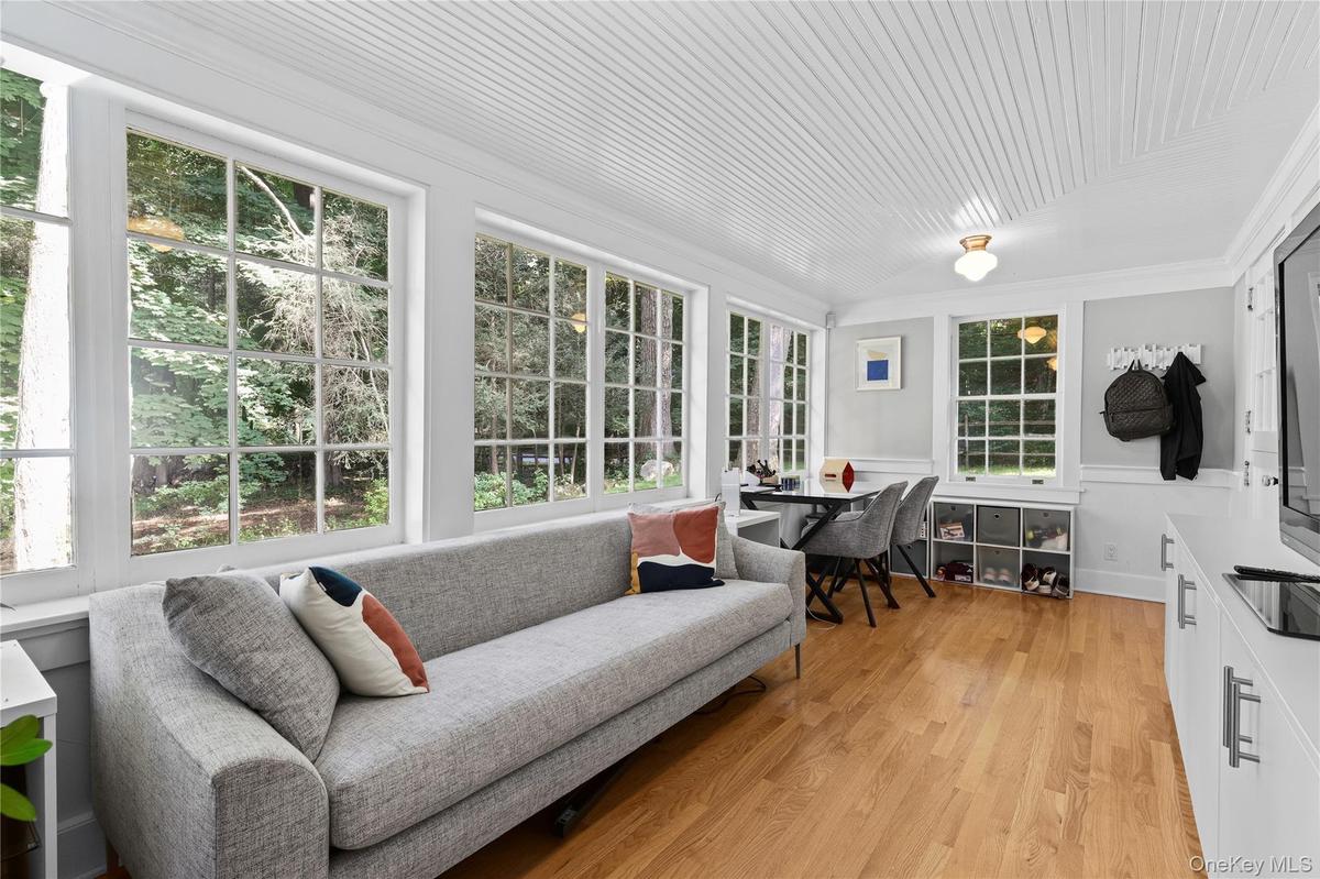 Sun room featuring wood-finish flooring, beadboard ceiling, and multiple grid-pattern windows, and built-ins.