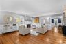 Spacious Living room featuring wood-finished flooring, white wainscoting, and a traditional fireplace.