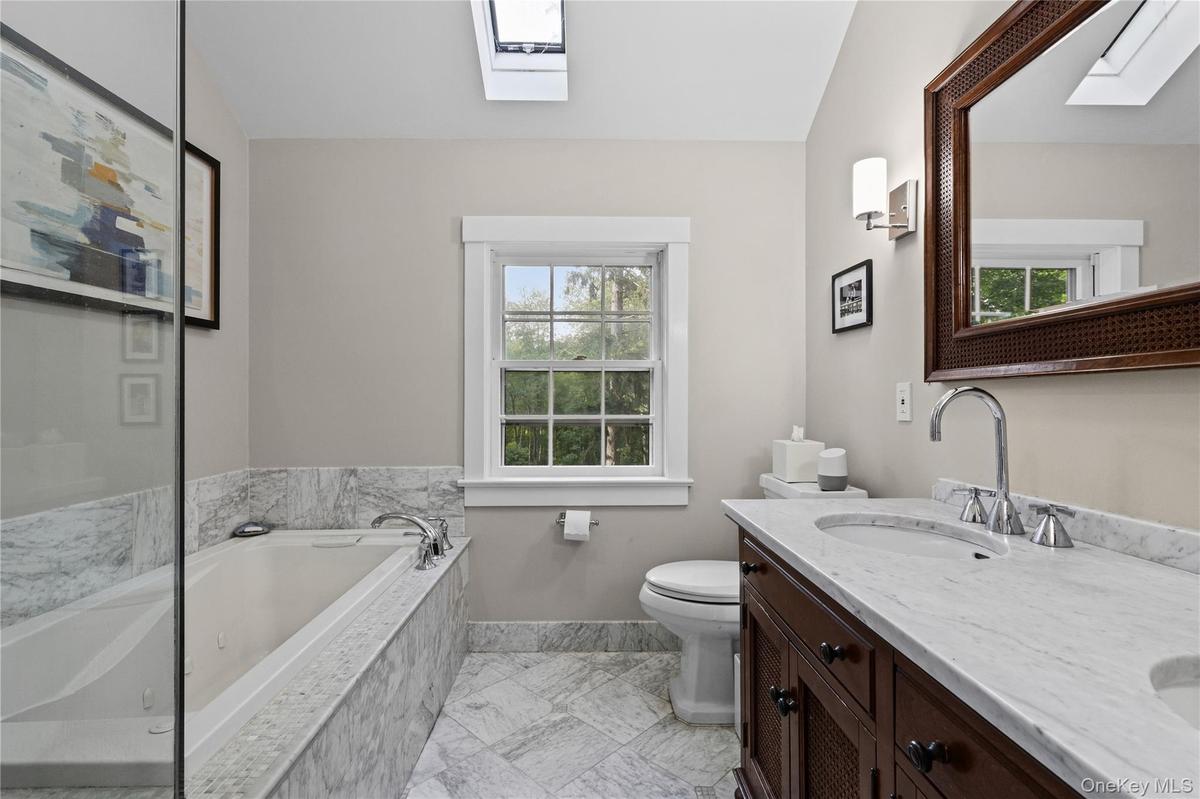 Primary Bathroom featuring a glass-enclosed shower with full tile surround, whirlpool tub with tile surround, and a dual vanity with undermount sinks 