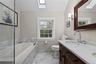 Primary Bathroom featuring a glass-enclosed shower with full tile surround, whirlpool tub with tile surround, and a dual vanity with undermount sinks 