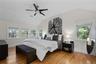 Primary Bedroom featuring vaulted ceilings, a ceiling fan, wood-finish flooring, and multiple windows.